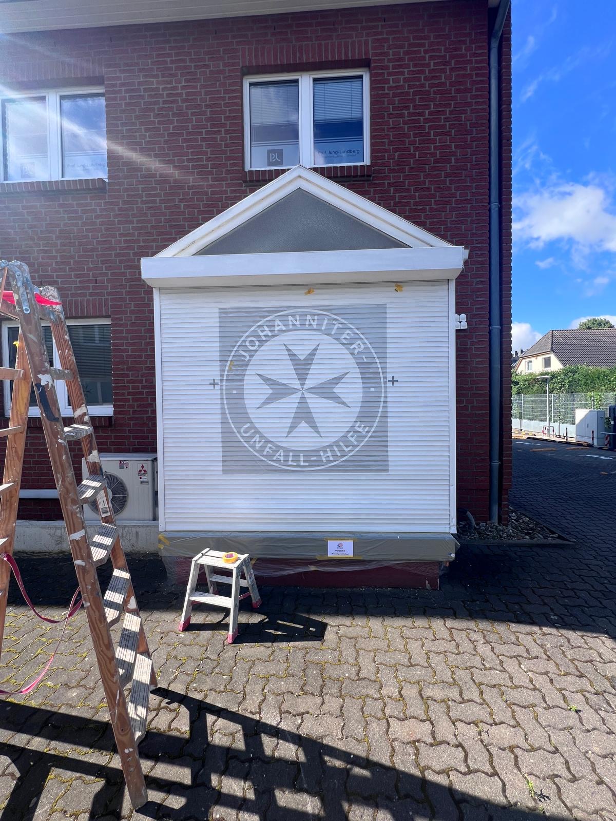 Frisch weiß lackierte Holzverkleidung an einem Anbau mit Emblem im Giebel