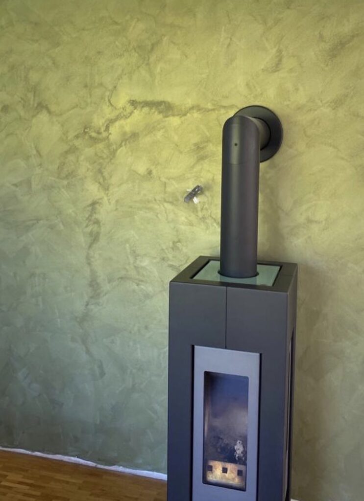 Spachteltechnik in Grüntönen hinter einem Kaminofen
